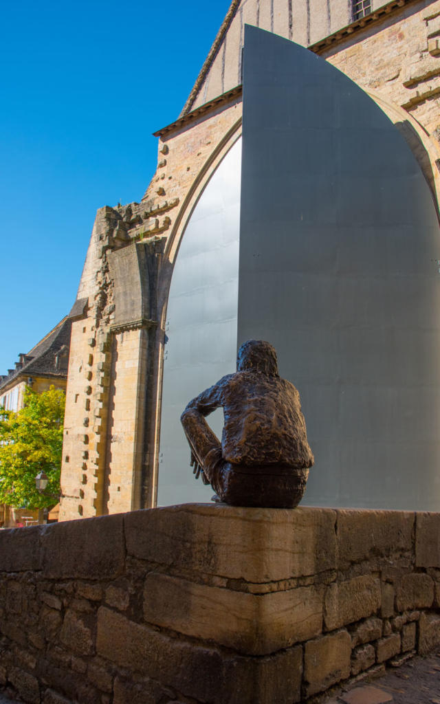 Statue du Badaud à Sarlat devant les portes de l'ancienne église Sainte-Marie