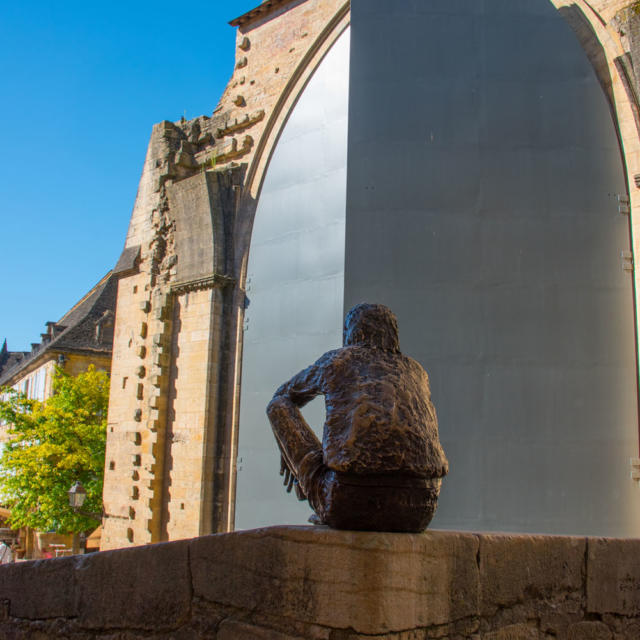 Statue du Badaud à Sarlat devant les portes de l'ancienne église Sainte-Marie