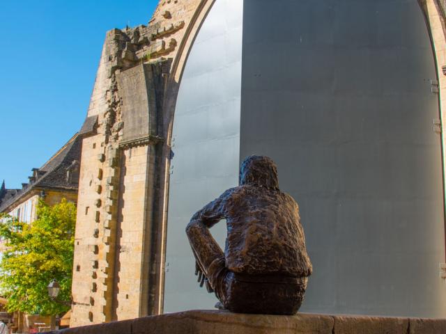 Statue du Badaud à Sarlat devant les portes de l'ancienne église Sainte-Marie